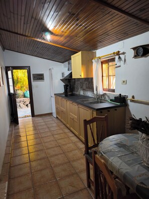 Una cocina con armarios de madera, un lavamanos y un ventanal con cortinas.