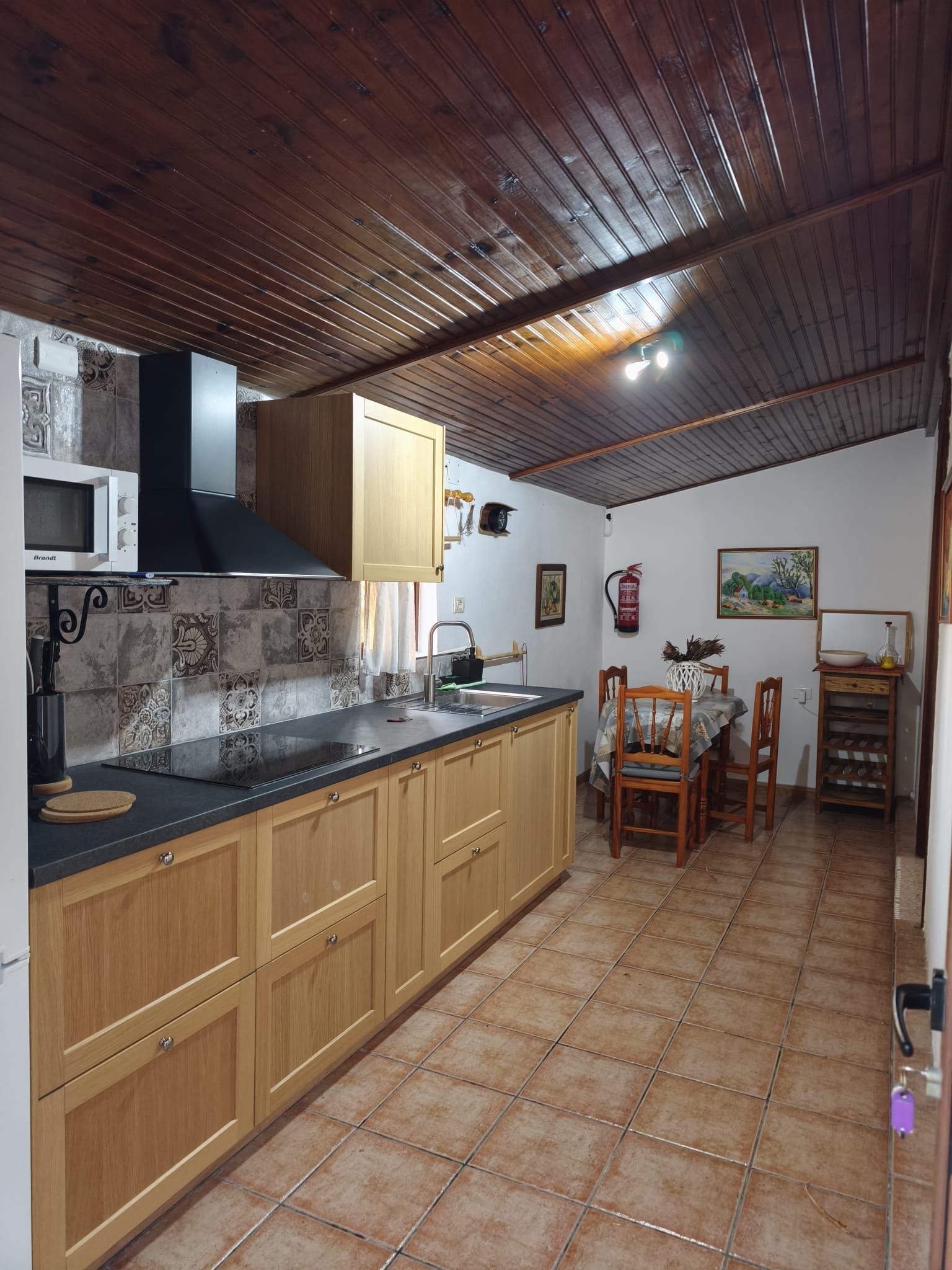 A kitchen with wooden cabinets, a black countertop, and a tiled backsplash.
