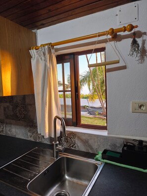 A kitchen with a stainless steel sink, a window with a view of palm trees, and a wooden ceiling. - Apartment Padres A for 4 people (Santa Cruz de Tenerife)