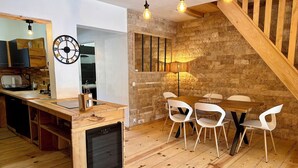 A modern kitchen with wooden countertops, a built-in dishwasher, and a dining area with a wooden table and white chairs. - Alba | Air-conditioned, Wi-Fi, PMR, beach 20 metres away (Borgo)