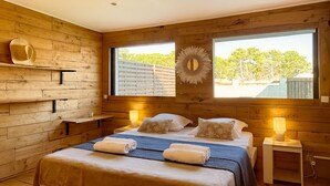 A wooden-paneled bedroom with a bed, bedside lamps, and a large window. - Alba | Air-conditioned, Wi-Fi, PMR, beach 20 metres away (Borgo)