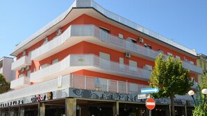 En byggnad med flera våningar och balkonger, en restaurang som heter ”Ostibar” på bottenvåningen och en skylt som visar vägen till gatan ”Atlante”.