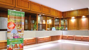 Un hall d'accueil d'hôtel avec des panneaux de bois et une grande enseigne indiquant que le pub et le restaurant sont ouverts.