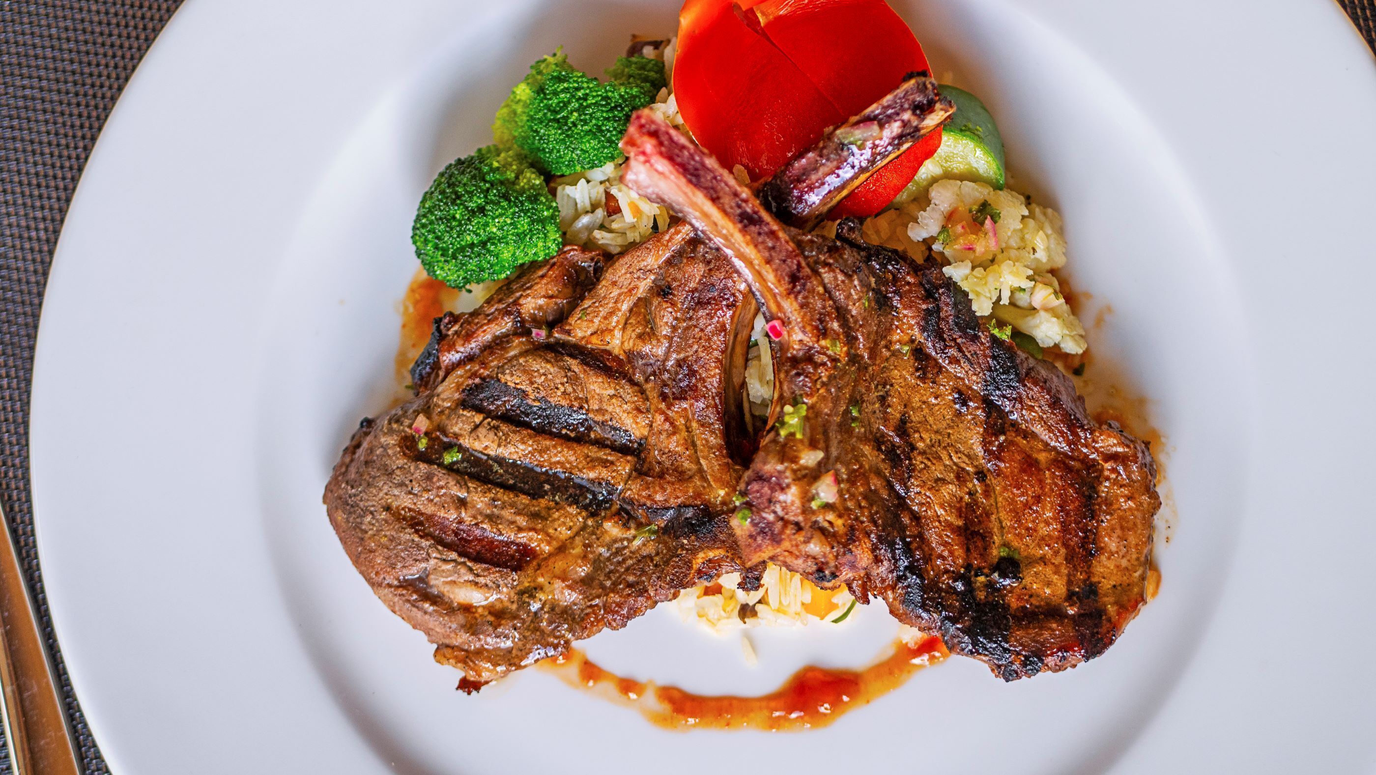 Een bord met gegrilde steak, broccoli en een plakje tomaat.