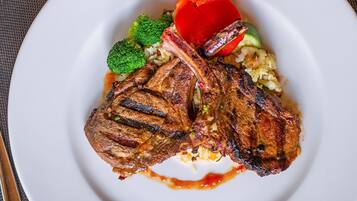 Un plato con bistec a la parrilla, brócoli y una rodaja de tomate.