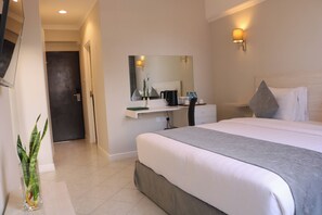 A hotel room with a large bed, a bedside table with a lamp, a mirror, and a small plant. - Maanzoni 680 hotel (Nairobi)