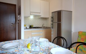 Enjoy meals in this cozy kitchen with a dining table for four, featuring a gas stove and refrigerator.