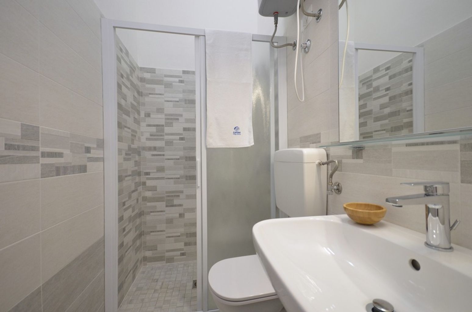 Ein Badezimmer mit Dusche, Toilette, Waschbecken und Spiegel.