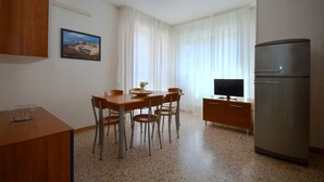 Una cuina compacta amb taula de menjador, caires, nevera i televisió.