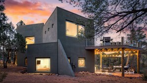 A modern two-story building with large windows and a covered outdoor seating area. - Scenic Views with Pool Table & Hot Tub | Cathedral View by AvantStay (Sedona)
