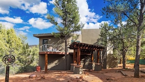 A modern house with a balcony, surrounded by trees and a clear sky. - Scenic Views with Pool Table & Hot Tub | Cathedral View by AvantStay (Sedona)