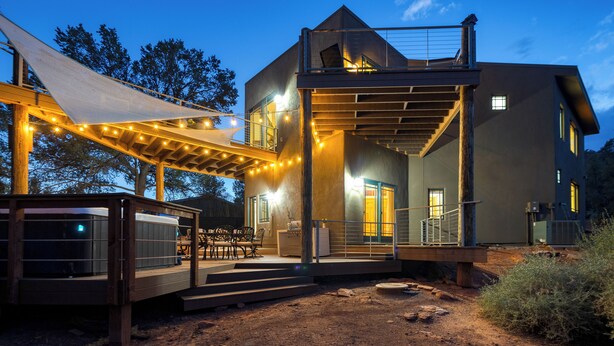 A modern two-story house with a covered patio, outdoor seating, and a dirt ground. - Scenic Views with Pool Table & Hot Tub | Cathedral View by AvantStay (Sedona)