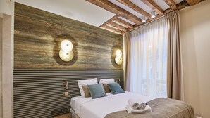 A modern bedroom with a wooden slat headboard, a bed with white linens, two wall-mounted lights, and a window with curtains. - Sublime Apartment Rue Royale/madeleine (Paris)