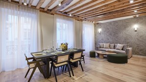 A dining area with a wooden table and chairs, a sofa, and a patterned wall. - Sublime Apartment Rue Royale/madeleine (Paris)