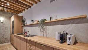A modern kitchen with wooden cabinets, a built-in sink, and a countertop with a toaster and kettle. - Sublime Apartment Rue Royale/madeleine (Paris)