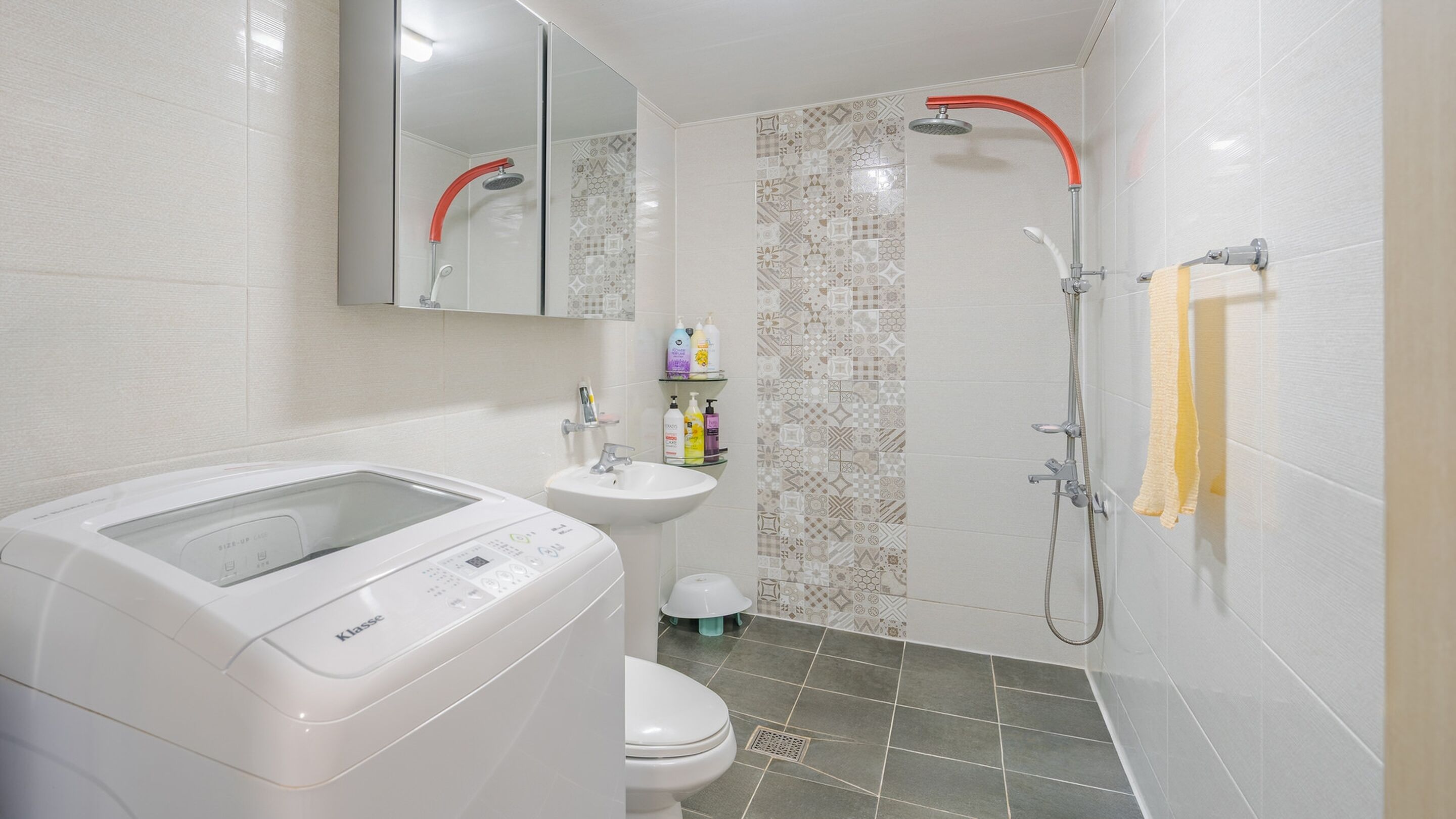 Un baño con lavadora, lavamanos, inodoro y ducha.