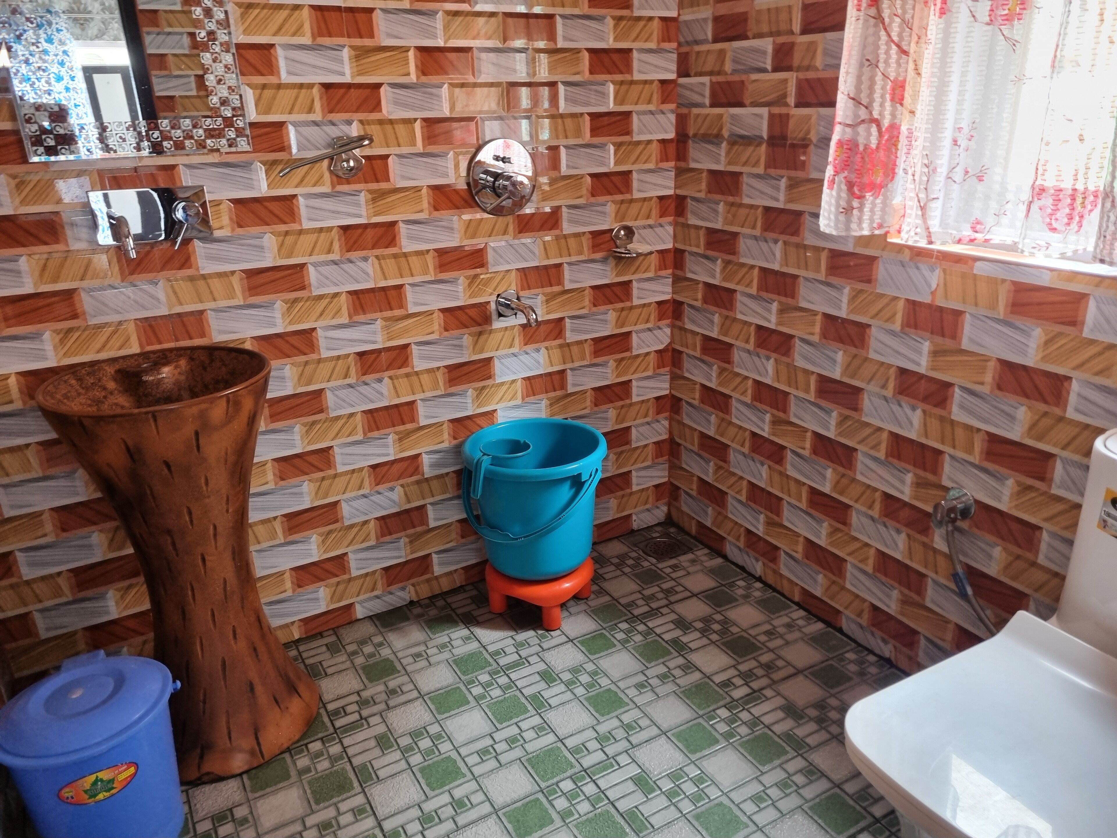 Un baño con pared de azulejos, un lavabo, un inodoro y un cubo azul.