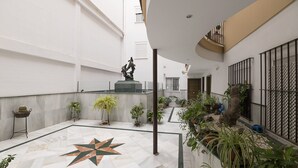 Un amplio patio interior con suelo de baldosas, un diseño decorativo de estrella en el centro y diversas plantas en macetas.