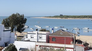 Vista costera con barcos en el agua, una playa de arena y edificios en primer plano.