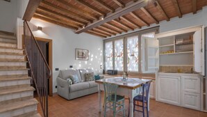 A spacious living area with a dining table, chairs, a sofa, and a staircase. - La Capanna, Borgo Campassini, Monteriggioni (Monteriggioni)
