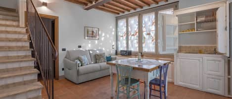 A spacious living area with a dining table, chairs, a sofa, and a staircase.
