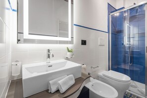 Une salle de bain moderne avec une grande baignoire blanche, des toilettes séparées et une douche à parois de verre.