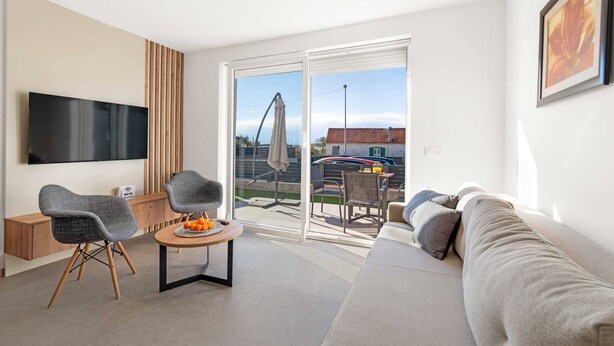 A modern living room with a sofa, two armchairs, a coffee table, and a flat-screen TV mounted on the wall. - Apartments Velic - apartment with terrace B (Šibenik-Brodarica)