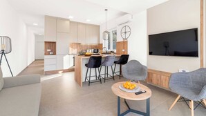 A modern living room with a sofa, a coffee table with fruit, and a TV. - Apartments Velic - apartment with terrace B (Šibenik-Brodarica)