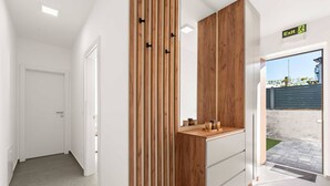 A modern hallway with a wooden accent wall, a small counter with jars, and an exit sign. - Apartments Velic - apartment with terrace B (Šibenik-Brodarica)