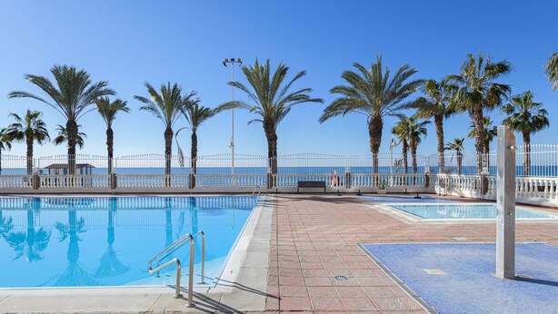 A pool area with a clear view of the sea, surrounded by palm trees and a white fence. - Algarrobo Costa - Apartment In Algarrobo-costa (Algarrobo Costa, Málaga)