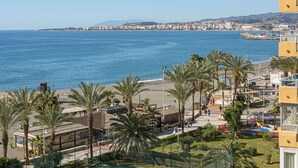 A coastal view with a beach, palm trees, and a cityscape in the background. - Algarrobo Costa - Apartment In Algarrobo-costa (Algarrobo Costa, Málaga)