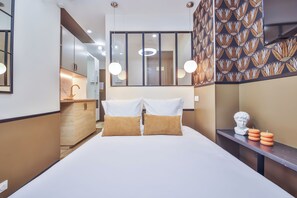 Una habitación de hotel moderna con una cama grande, un tocador con espejo y una pared con estampado.