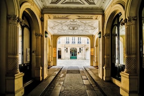 An ornate hallway with classical architecture, including columns and a detailed ceiling. - WS - Opéra - Malesherbes (Paris)