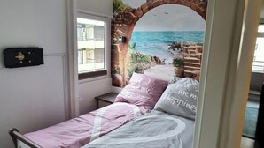 A bedroom with a bed, a window, and a mural of a beach scene. - Welcome to apartment 20 in house 1 of the Vier Jahreszeiten complex (Großenbrode)