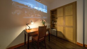 A room with a wooden desk, a chair, a lamp, a projector screen displaying a cityscape, and a wooden wardrobe. - Shine Hue Hotel 2  (Hue)