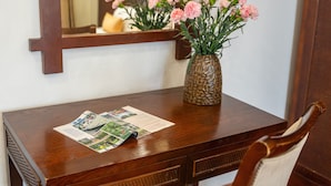 A wooden table with a vase of pink flowers and a brochure. - Shine Hue Hotel 2  (Hue)