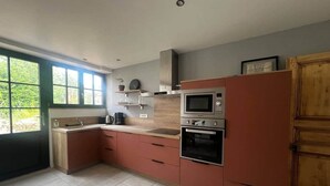 A modern kitchen with a large window, built-in oven, microwave, and a wooden cabinet.