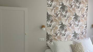 A bedroom with a bed, a wardrobe, a wall-mounted light, and a power outlet.