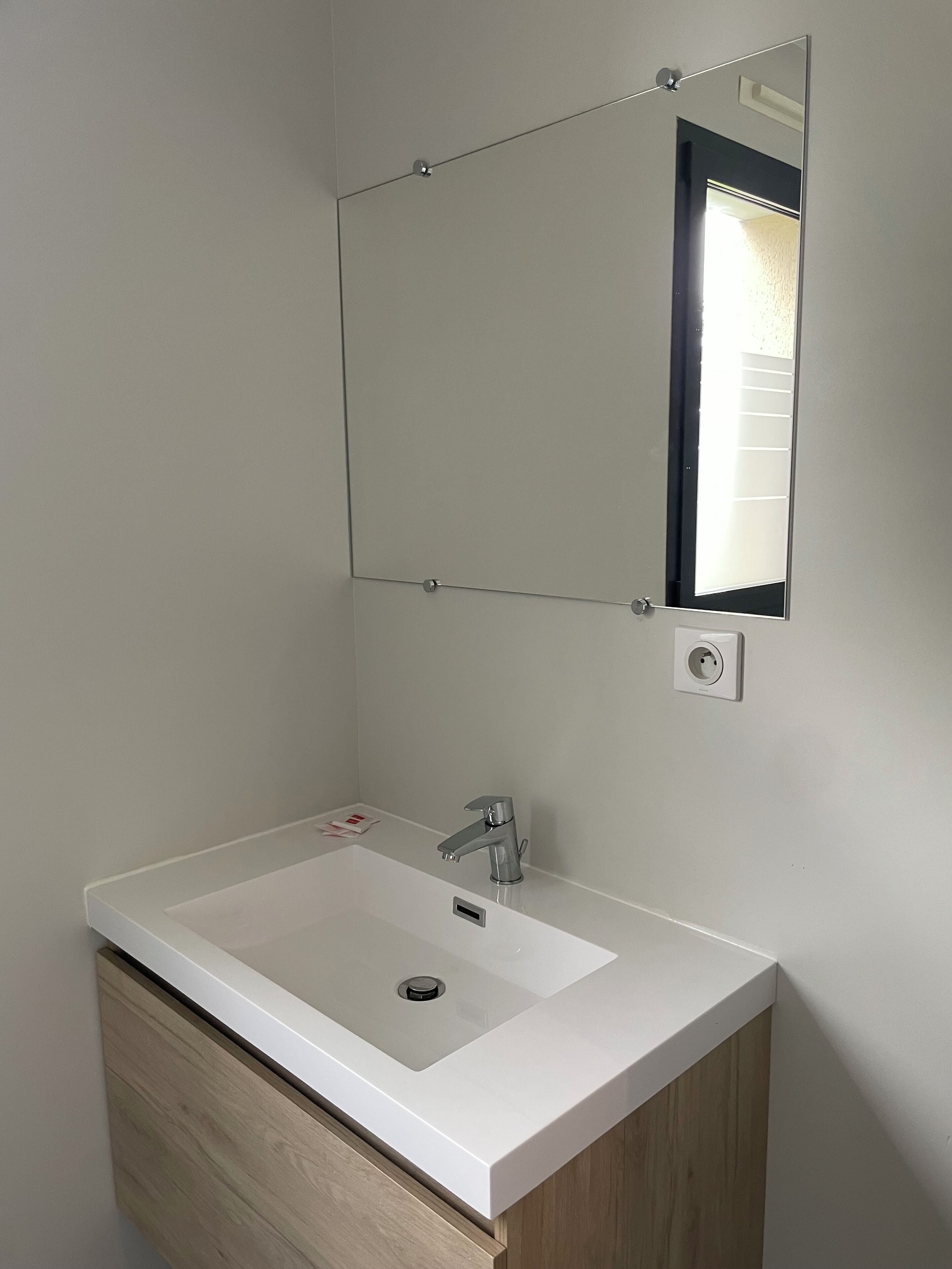 Un baño con un lavabo blanco, un espejo y un armario de madera.
