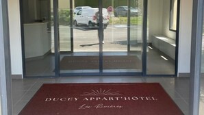 A hotel entrance with a glass door, a red carpet, and a sign that reads "DUCLEY APART' HOTEL Les Rivières." - Ducey Appart'hôtel  (Ducey-les-Chéris)