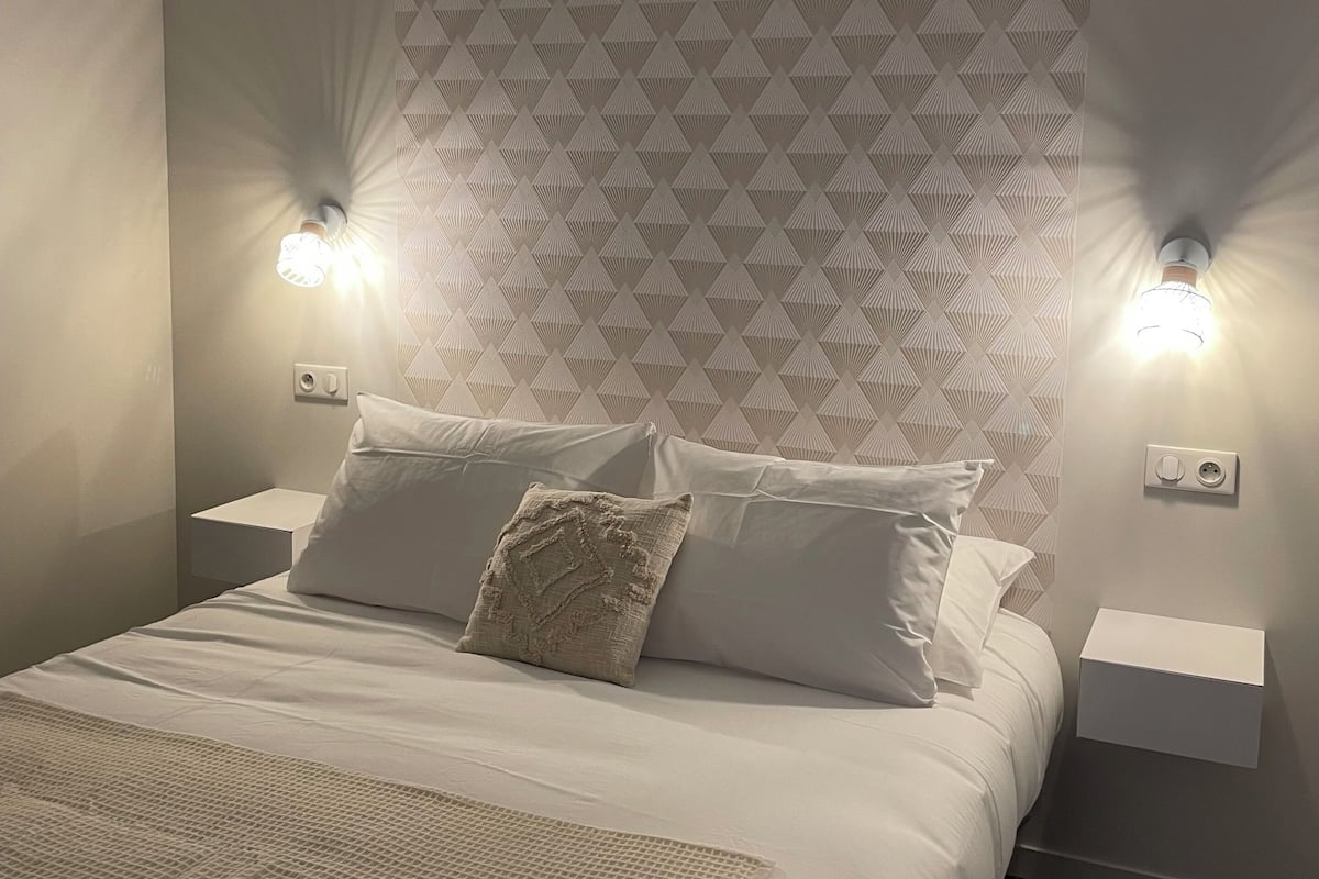A bedroom with a bed, two bedside tables, and a patterned wall.