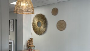 A reception area with a wooden counter, a woven pendant light, and decorative wall art. - Ducey Appart'hôtel  (Ducey-les-Chéris)