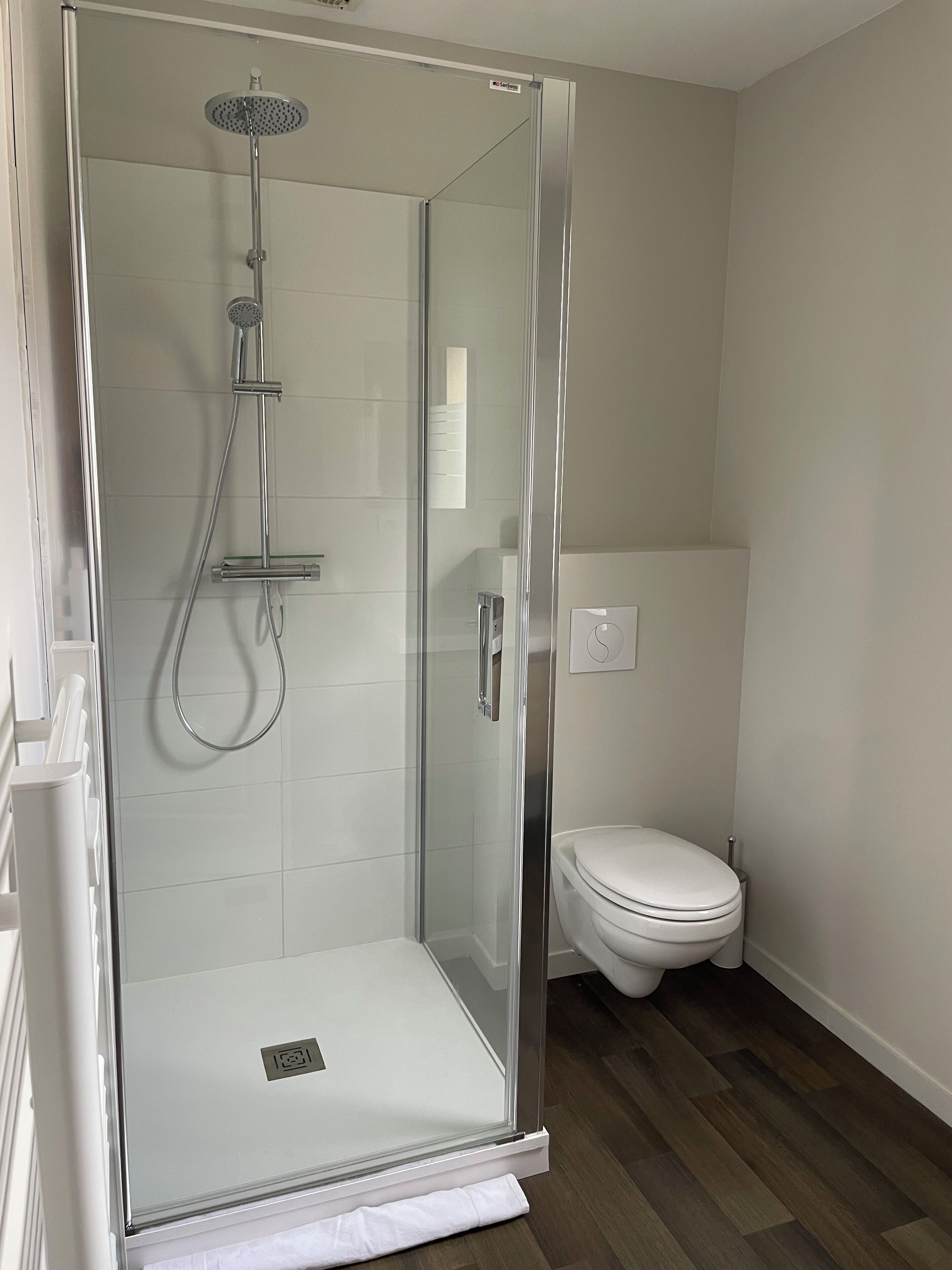 Une salle de bain moderne avec une douche à parois de verre, des toilettes et un lavabo blanc.