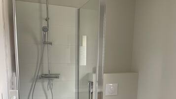 Une salle de bain moderne avec une douche à parois de verre, des toilettes et un lavabo blanc.