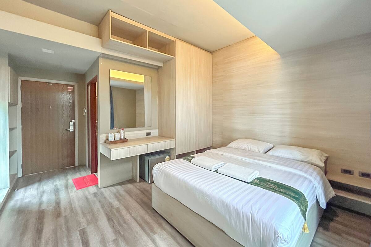 A modern hotel room with a large bed, a built-in vanity, and a mirror above the counter.