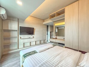 Ett modernt hotellrum med en säng, inbyggda hyllor, en platt-TV och en stor spegel.