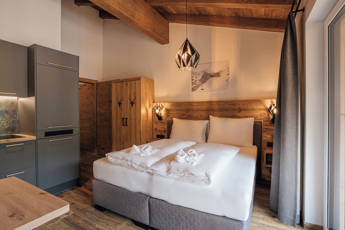 Un dormitorio moderno con cama, cabecera de madera y un armario gris.