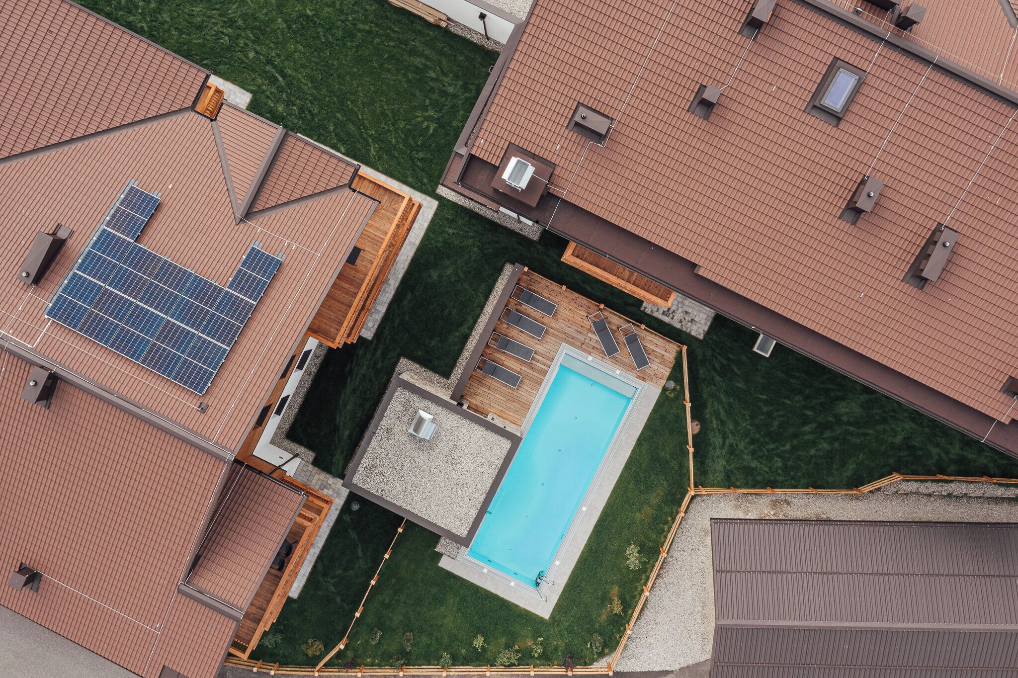 Zona residencial con piscina, paneles solares y patio cercado.