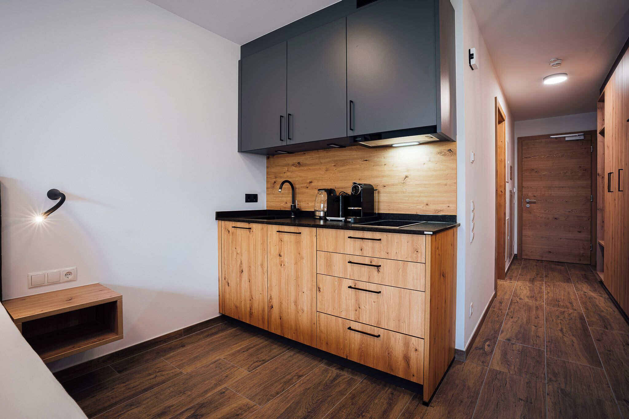 Een moderne keuken met houten kastjes, een zwart aanrecht en een ingebouwde kookplaat.