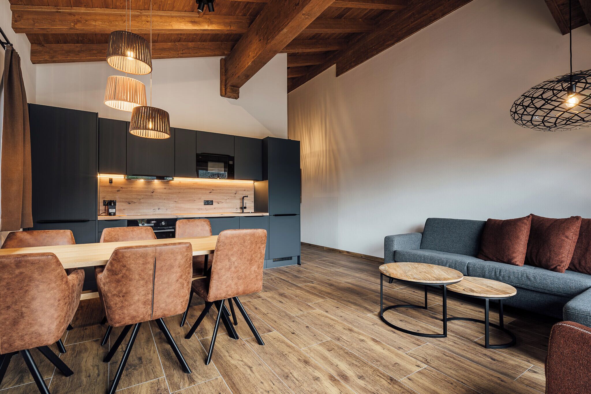 A modern kitchen with dark cabinets, a wooden countertop, and pendant lighting.